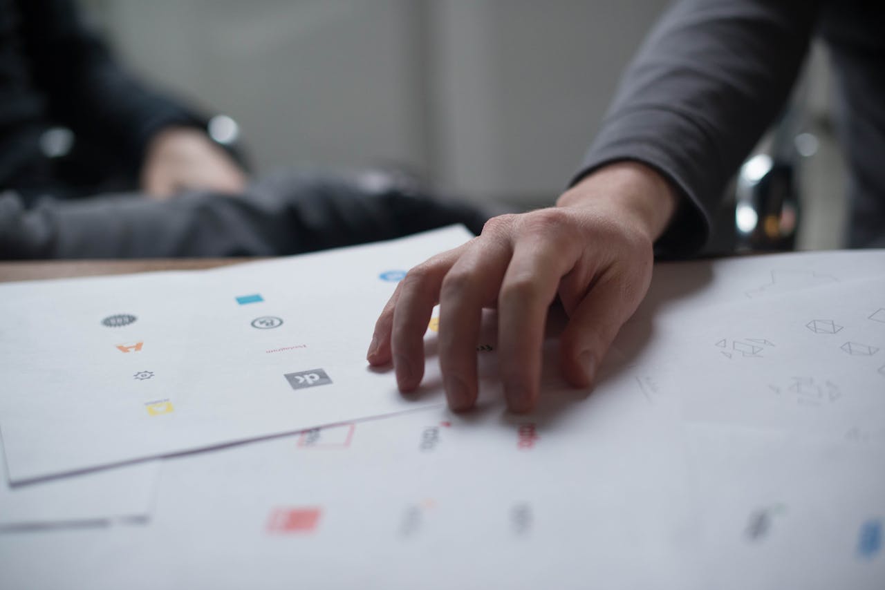 Home A close-up shot of a hand reviewing various logo designs on paper, ideal for business concepts.